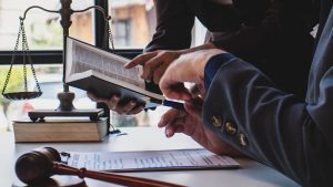 two lawyers discussing legislation over a book, multiple tools for law scattered over desk