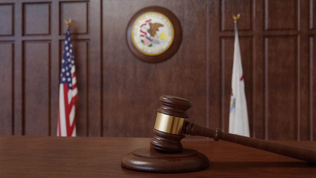 illinois board room with illinois and american flag in background, a gavel is in foeground